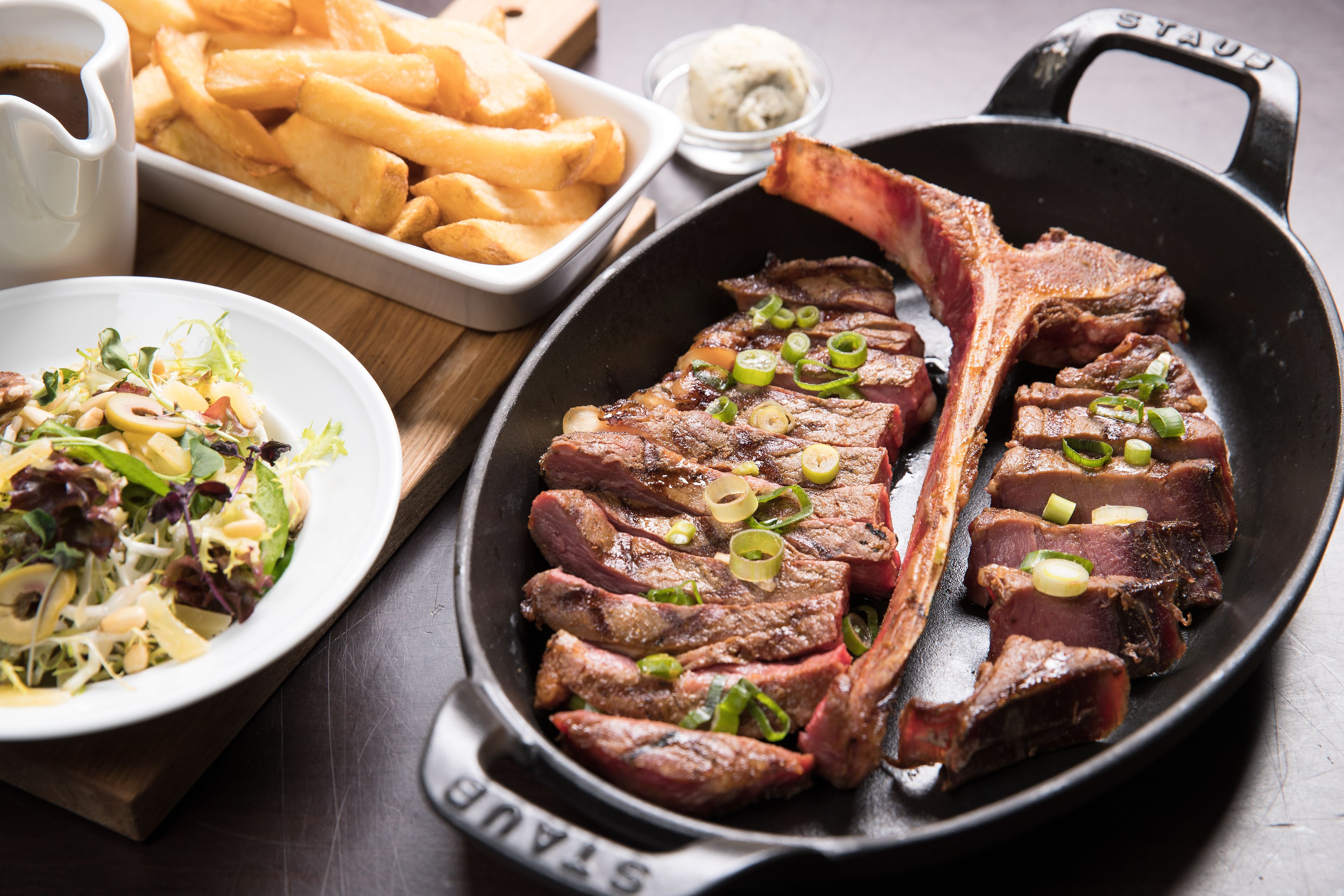 Een steak met friet op een houten tafel.
