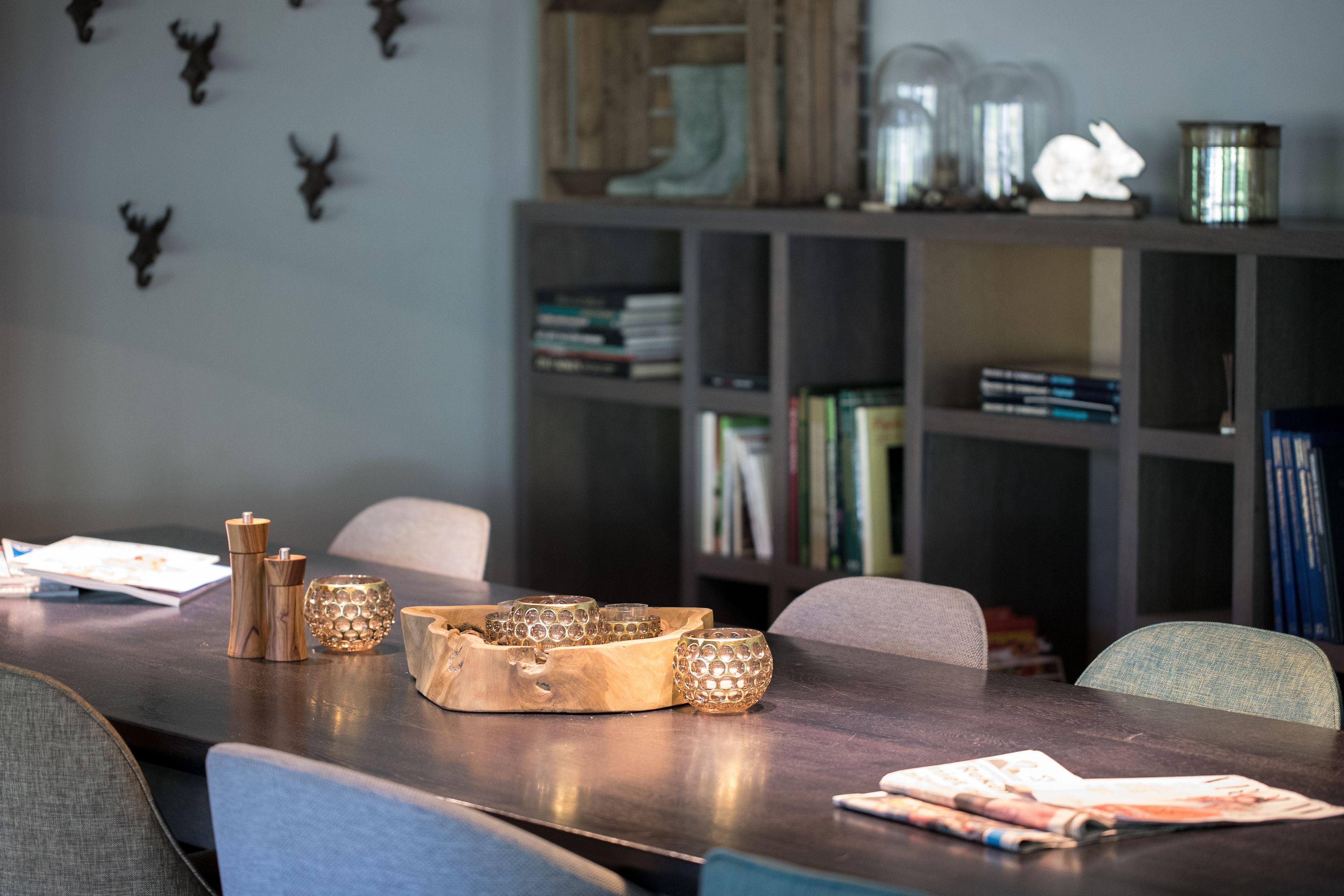 Een eettafel met een houten decoratie, boekenplanken en decoratieve objecten in een kamer.