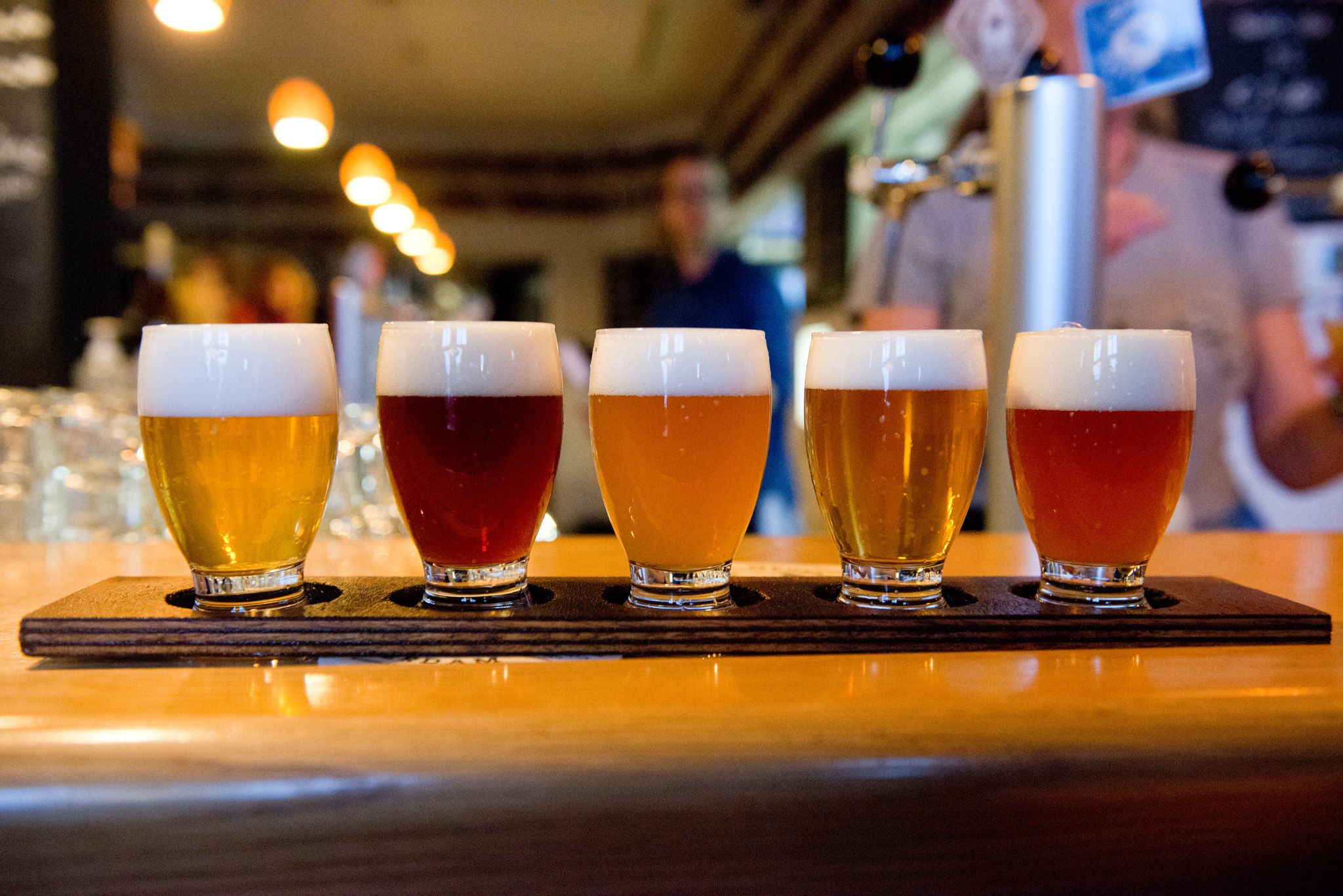 A bar with glasses of beer in a row.