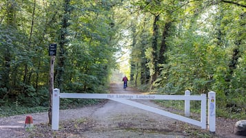 Een bebost pad met een witte poort waarop 'Het Limburgs Landschap' staat en een bord dat een parkeerplaats aangeeft.