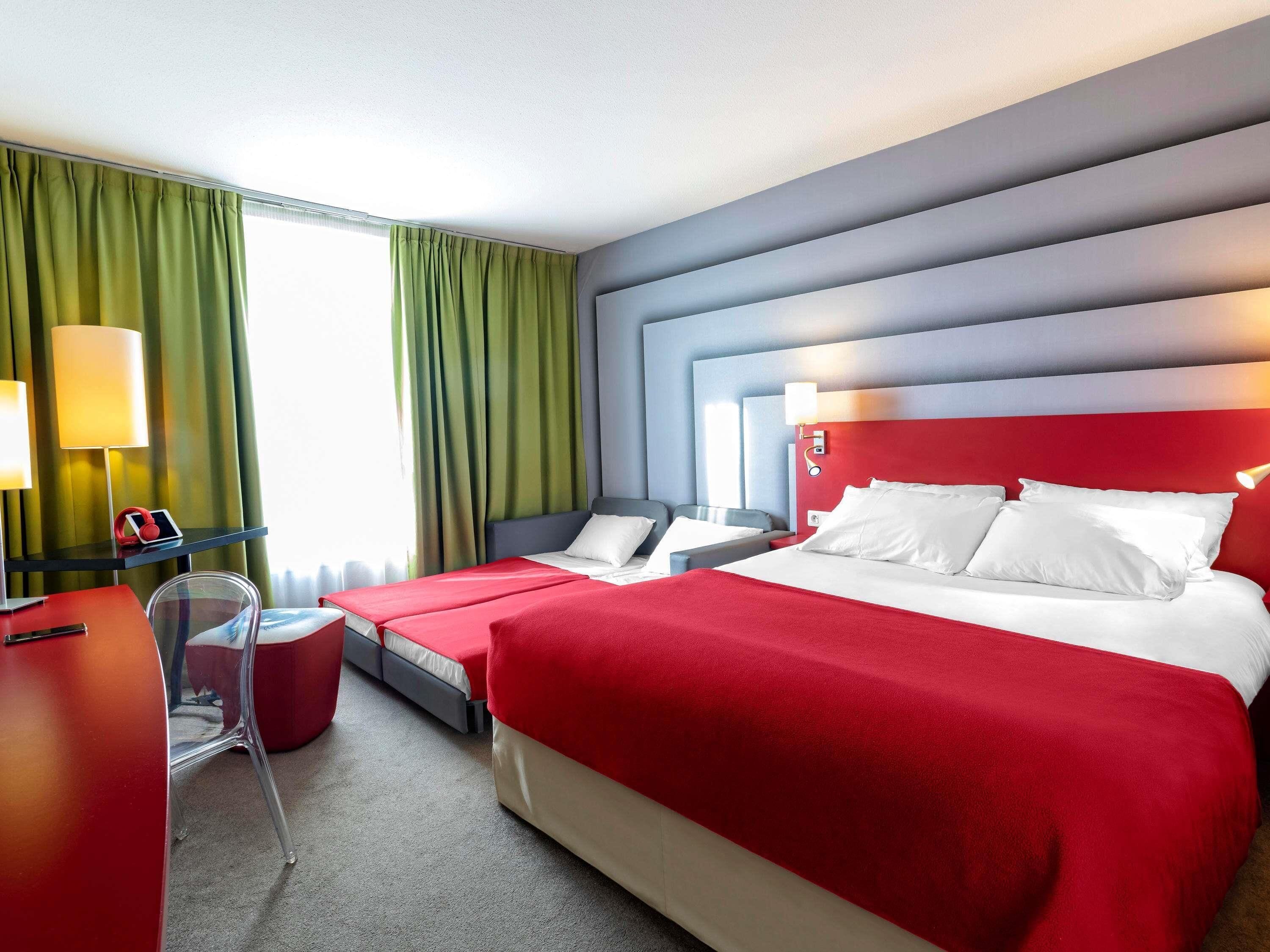 Ein Hotelzimmer mit zwei Betten, einem Schreibtisch und einem Stuhl.
