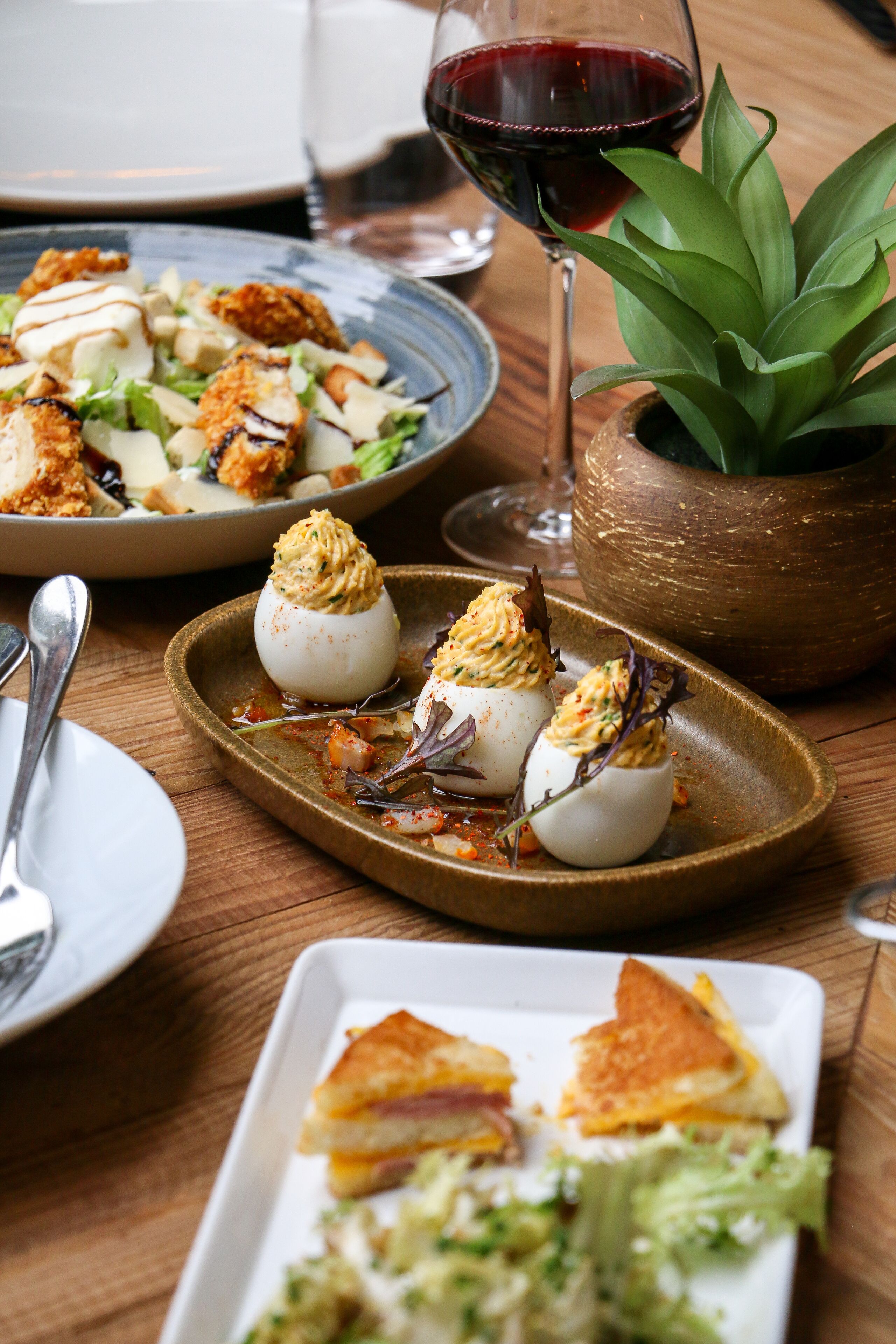 Une table à manger avec différents plats, notamment des œufs mimosa, une salade et un sandwich.