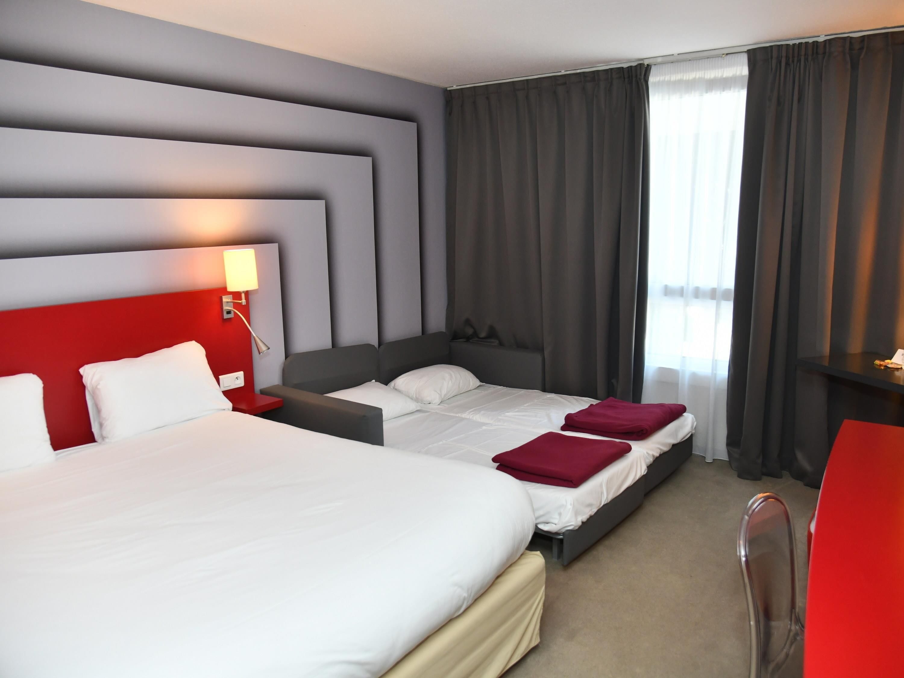A hotel room with two beds, a desk, and a chair.