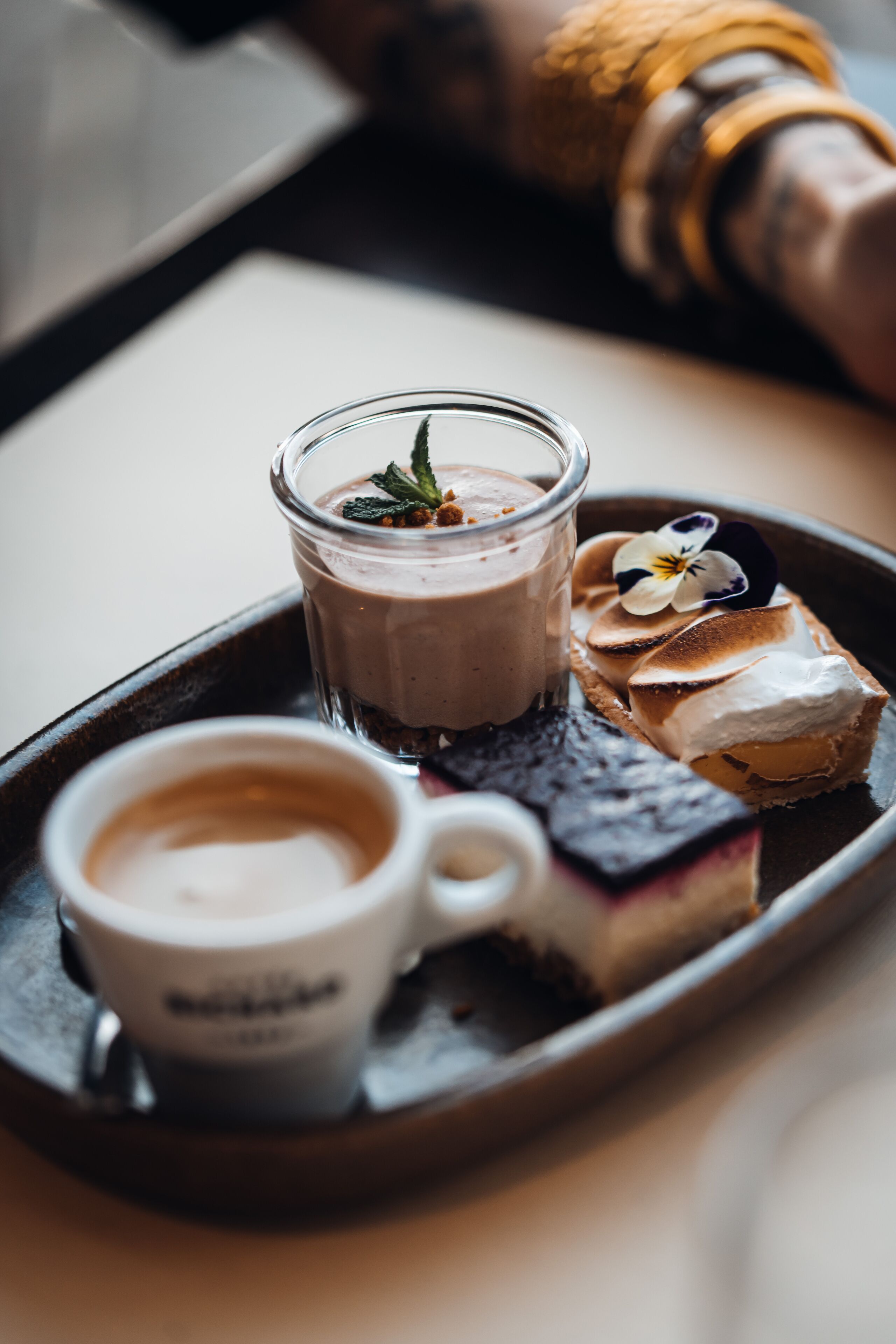 Un plateau avec un dessert, un verre de boisson au chocolat et une tasse de café.