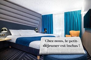 Moderni hotellihuone, jossa on siististi pedattu sänky, yöpöytä lampun kanssa ja tuoli. Sängyllä on sanomalehti, jossa on tekstiä ranskaksi.