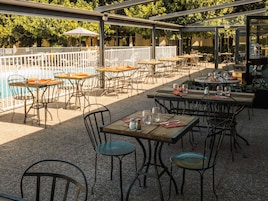 An outdoor patio with tables and chairs, a pool, and a covered seating area.