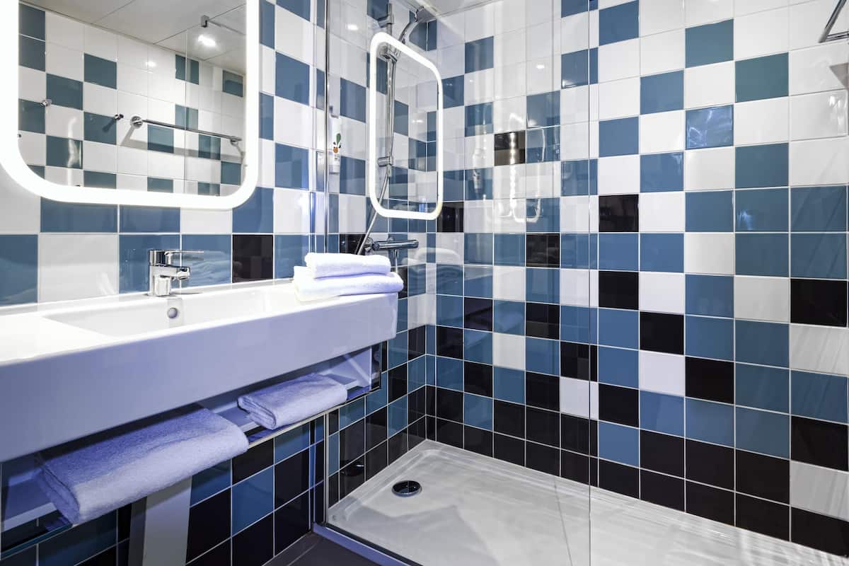A modern bathroom with a white sink, a mirror, and a shower area.