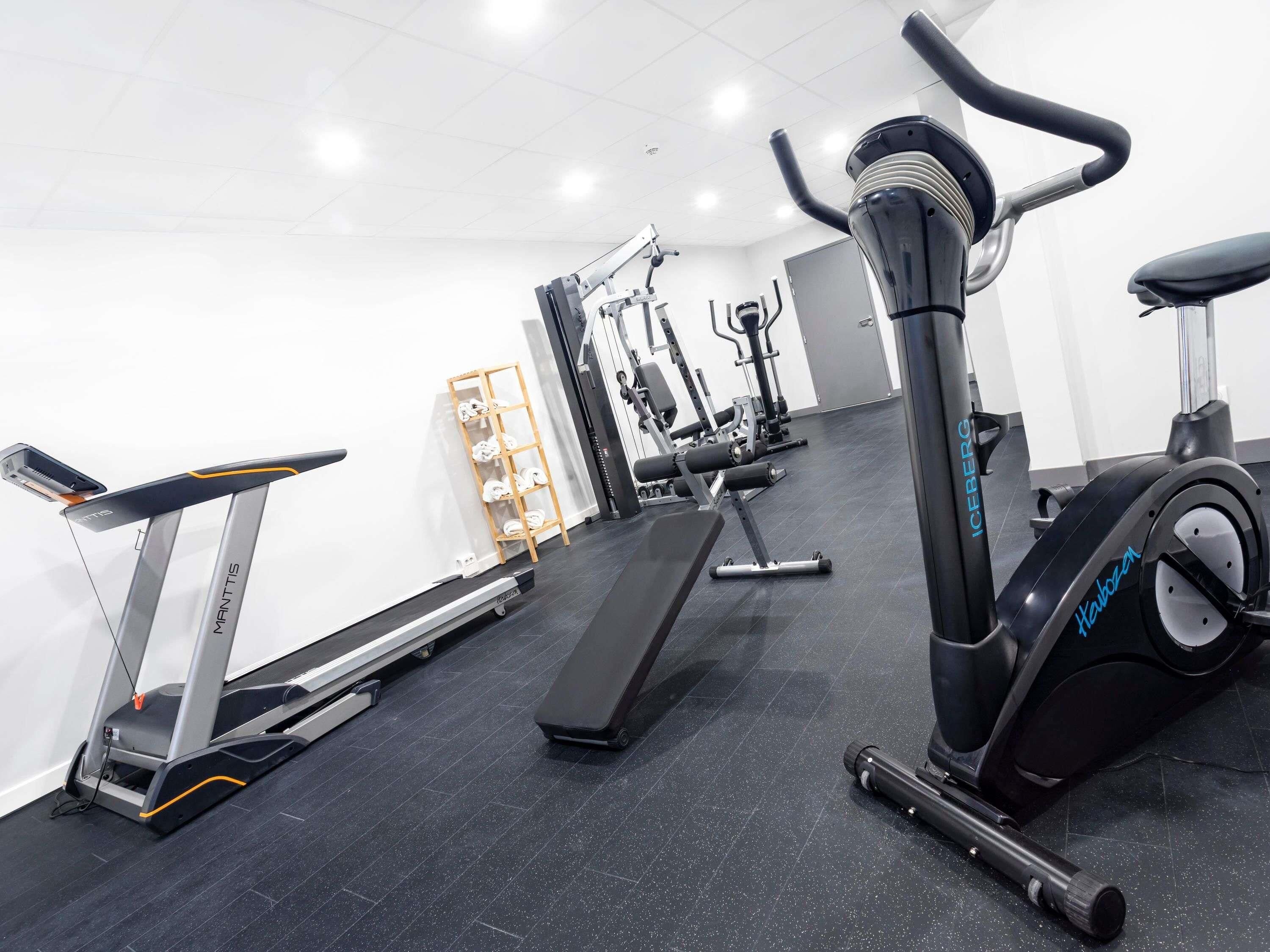 Un gimnasio con equipo cardiovascular, máquinas de pesas y una cinta de correr.