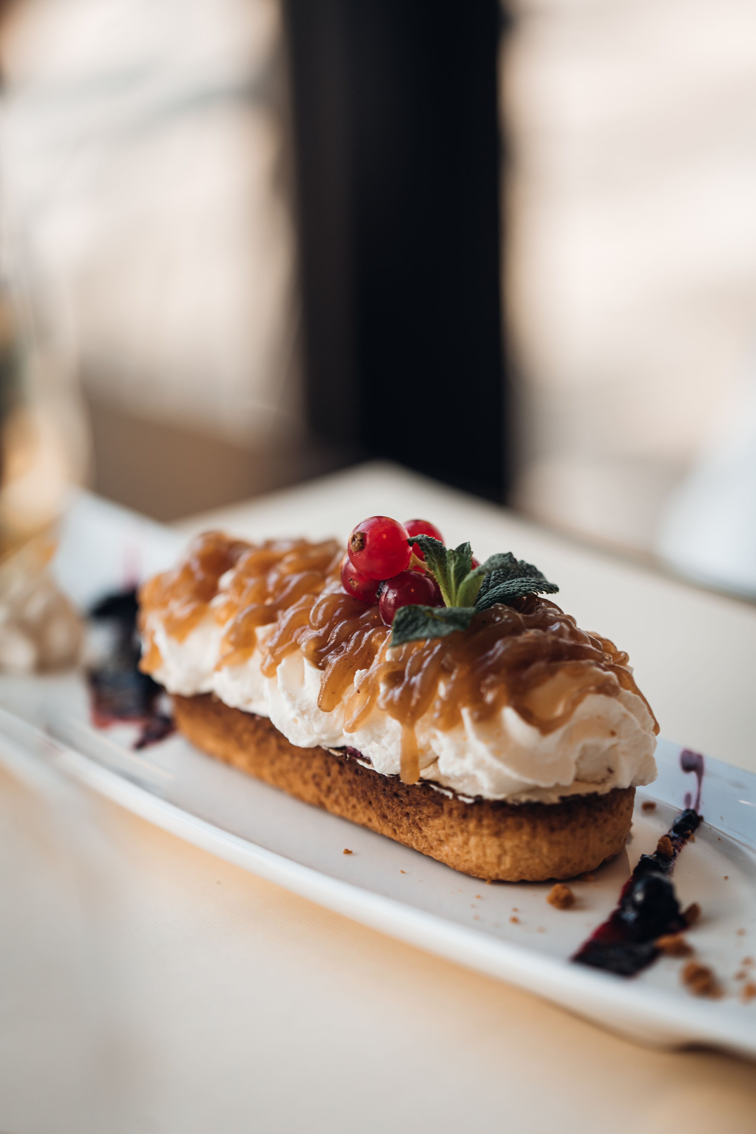 Ein Dessert auf einem weißen Teller mit Karamellsauce, Beeren und Minzblättern.