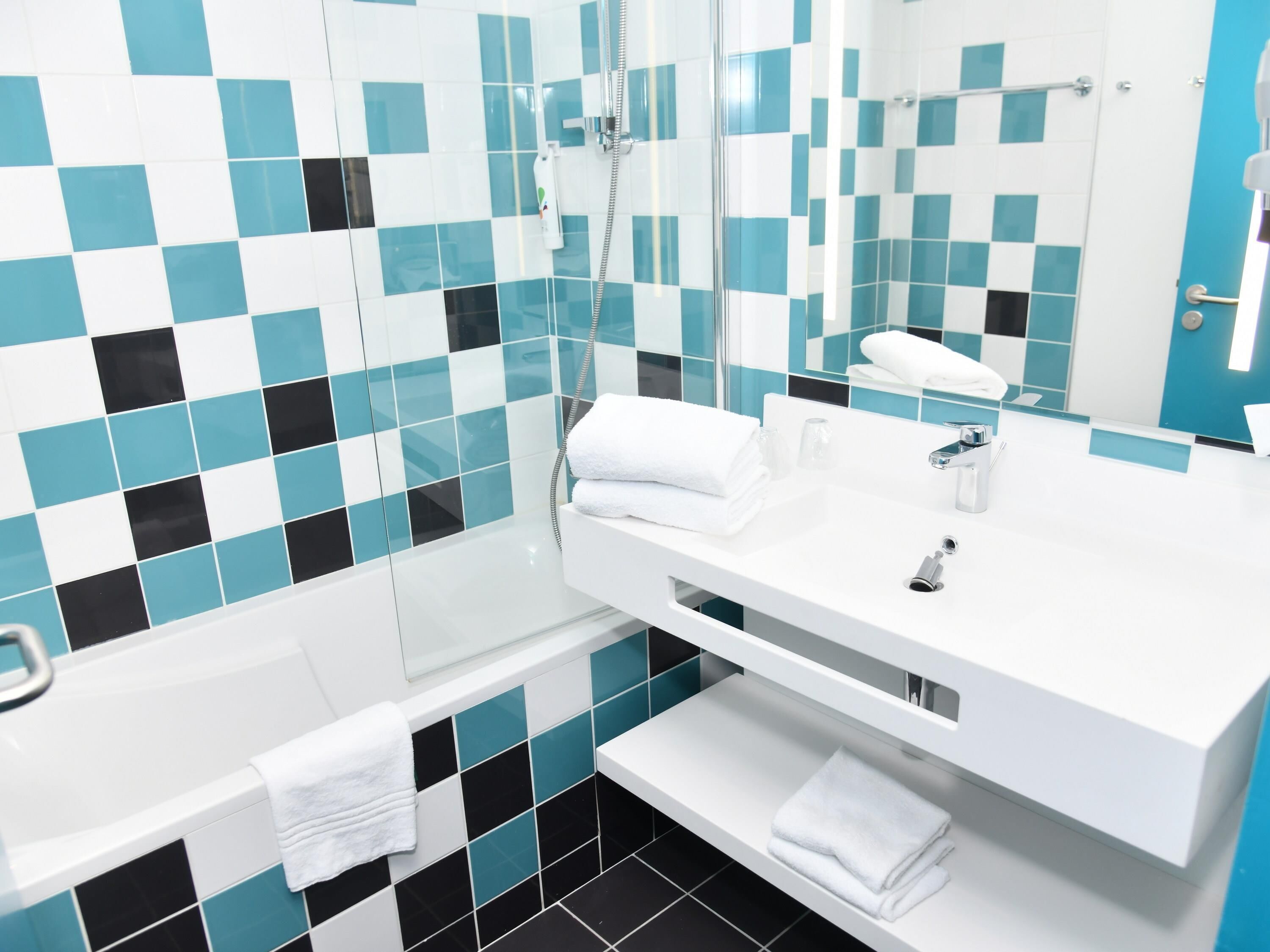 Un baño moderno con lavamanos blanco, espejo, ducha y bañera.