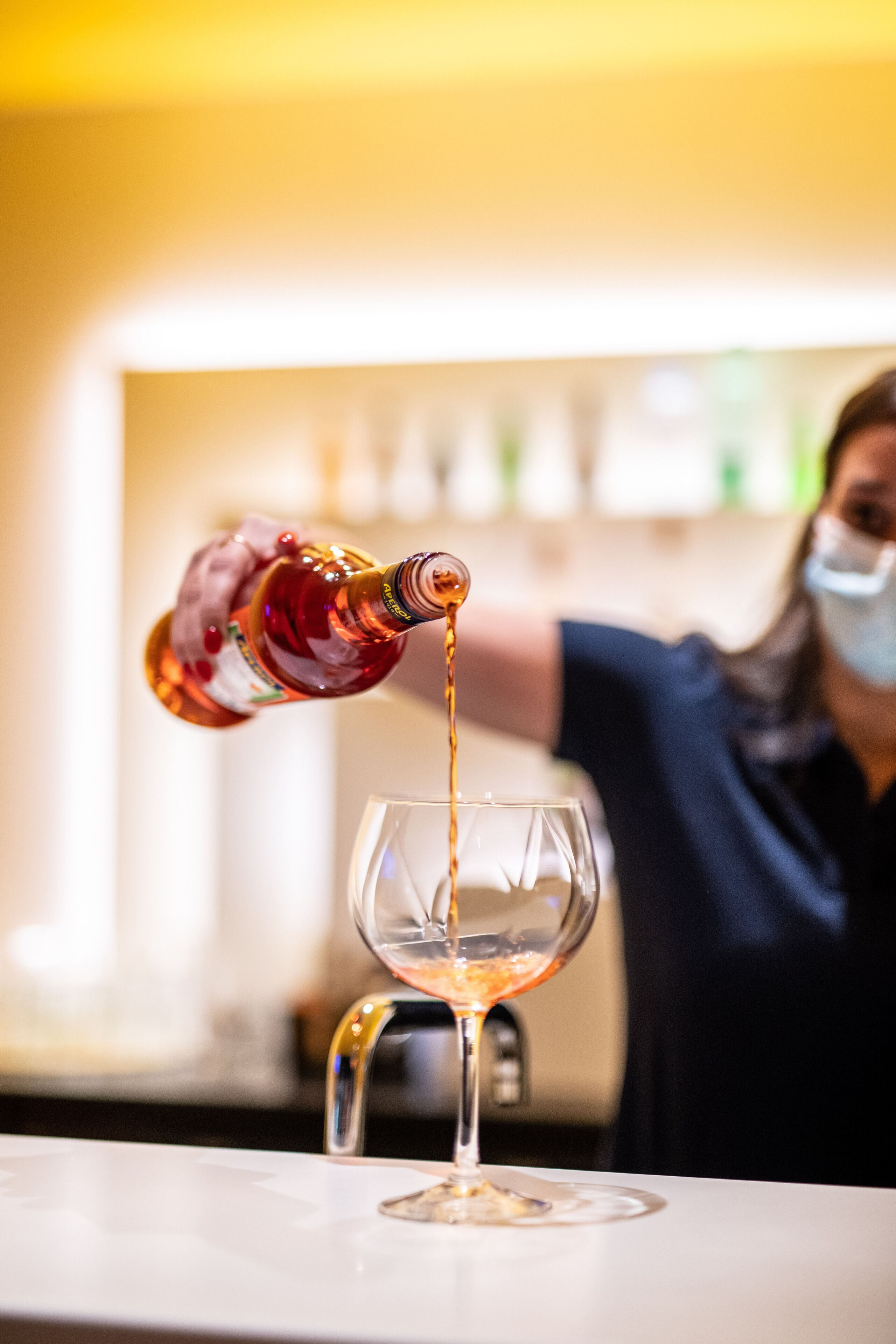 Una persona vertiendo un líquido desde una botella en un vaso transparente.