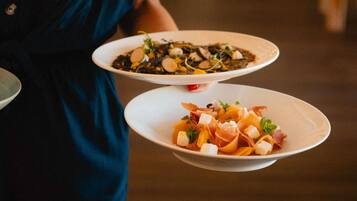 Two white plates with food, held by a person in a dark blue garment.