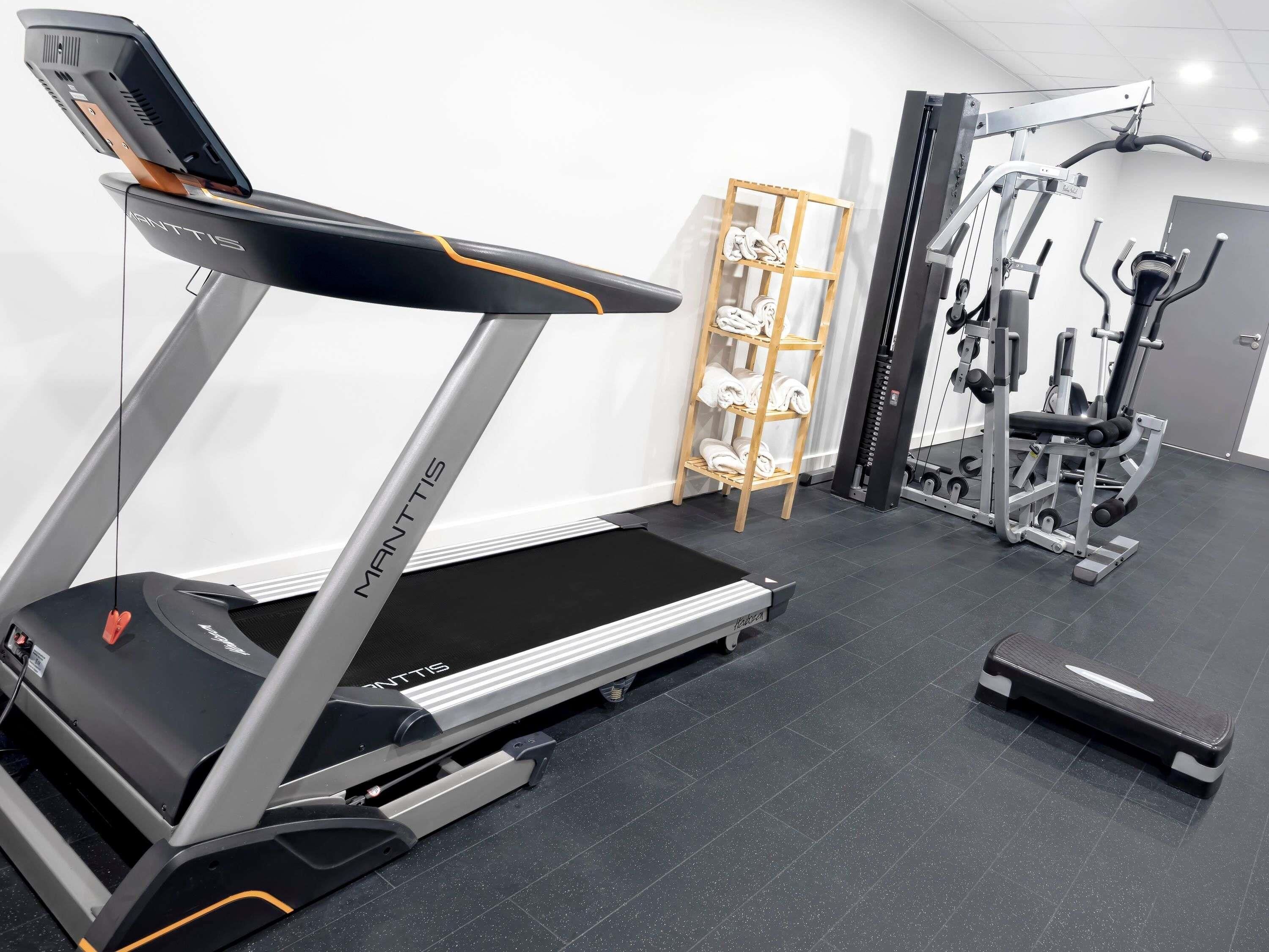 A gym with a treadmill, weight machines, and a step platform.