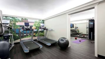 Un gimnasio en casa con cintas de correr, una bicicleta estática y pelotas de ejercicios.