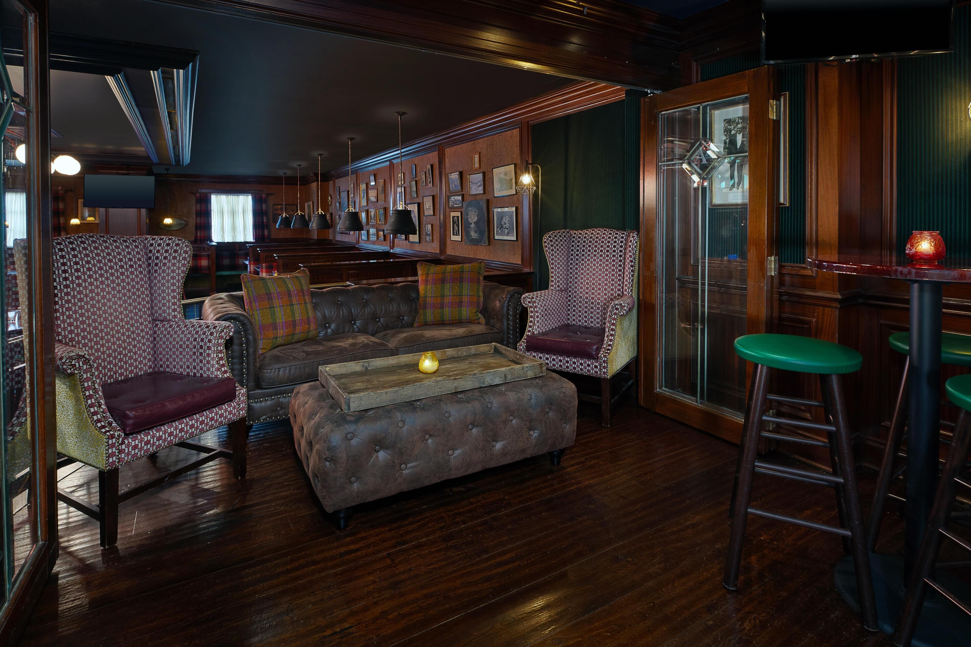 Zona de bar con paneles de madera, asientos de cuero y un taburete.