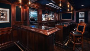 A bar area with wooden paneling, a bar counter, and a leather chair. - Graduate by Hilton Ann Arbor (Ann Arbor)