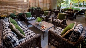 A cozy outdoor seating area with wicker furniture and green cushions. - Graduate by Hilton Ann Arbor (Ann Arbor)