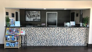 A reception area with a tiled counter, a framed welcome sign, a small plant, and a magazine rack. - Super 8 by Wyndham Terrell (Terrell)