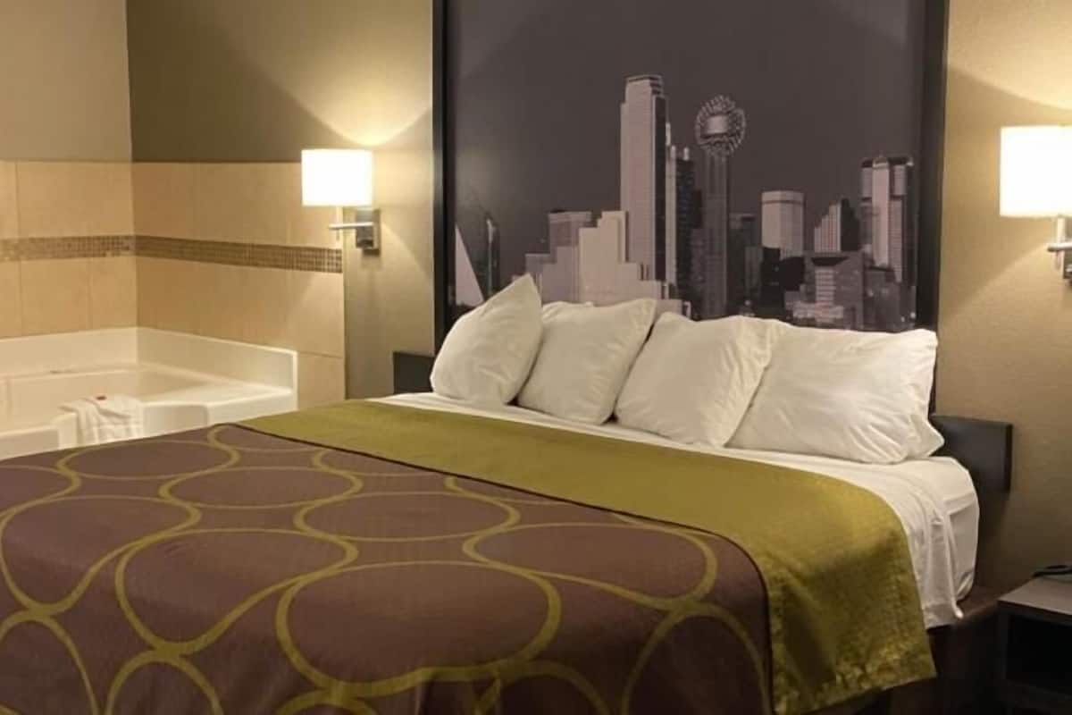 A hotel room with a bed, a bathtub, and a cityscape wall mural.