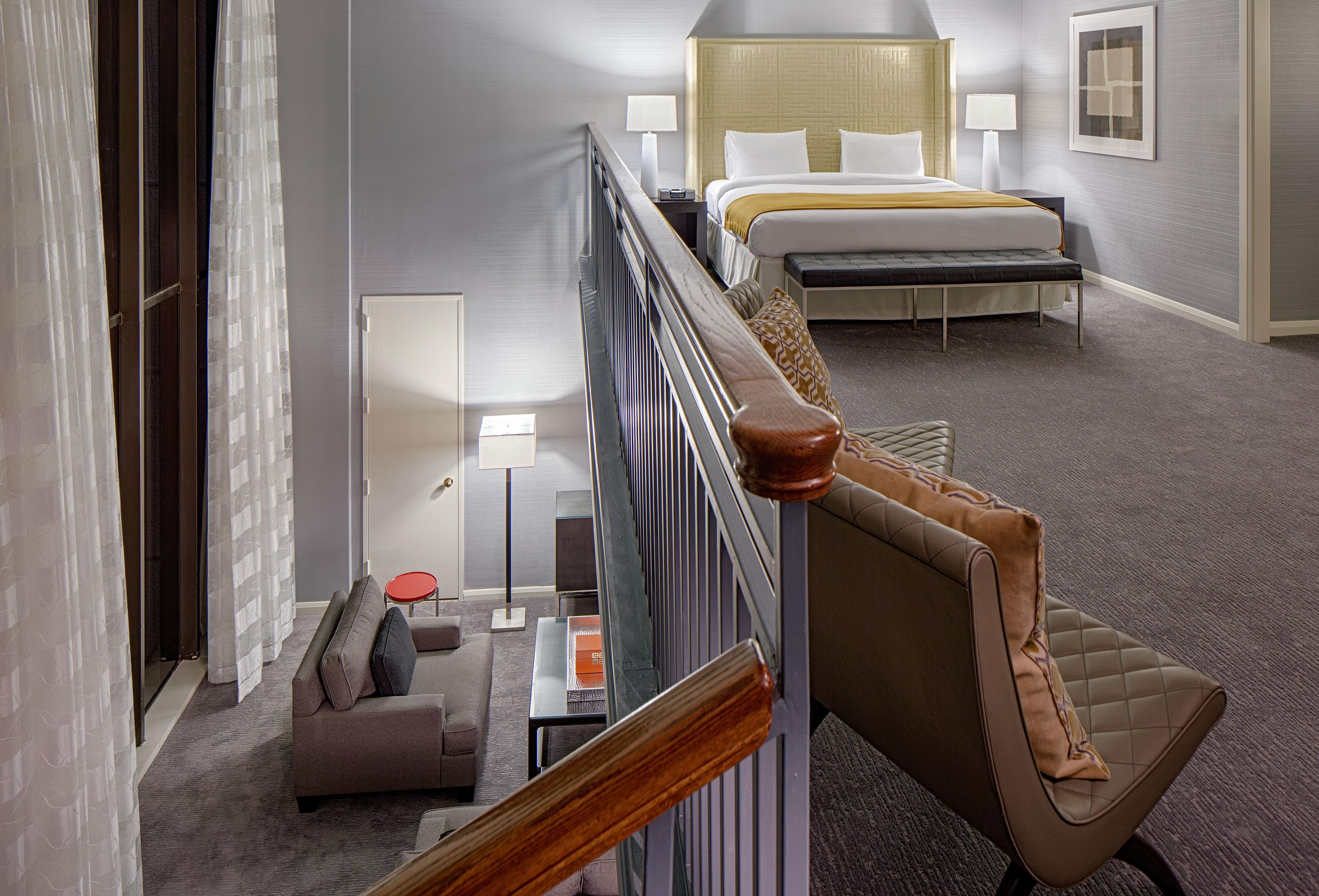 A hotel room with a bed, a sofa, a small table, and a chair.