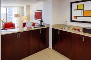 Una cocina de hotel con armarios de madera oscura, encimera de granito y pileta de acero inoxidable.