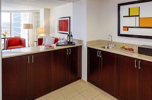 A hotel kitchen with dark wood cabinets, a granite countertop, and a stainless steel sink.