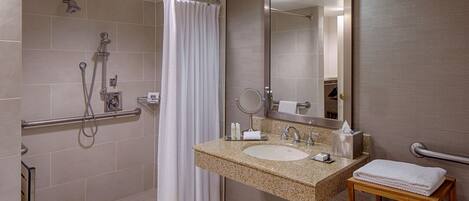 A modern bathroom with a shower, a sink, a mirror, and a towel rack.