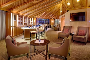 A hotel lobby with a bar area, seating arrangements, and a large TV screen. - DoubleTree by Hilton Hotel Houston - Greenway Plaza (Houston)