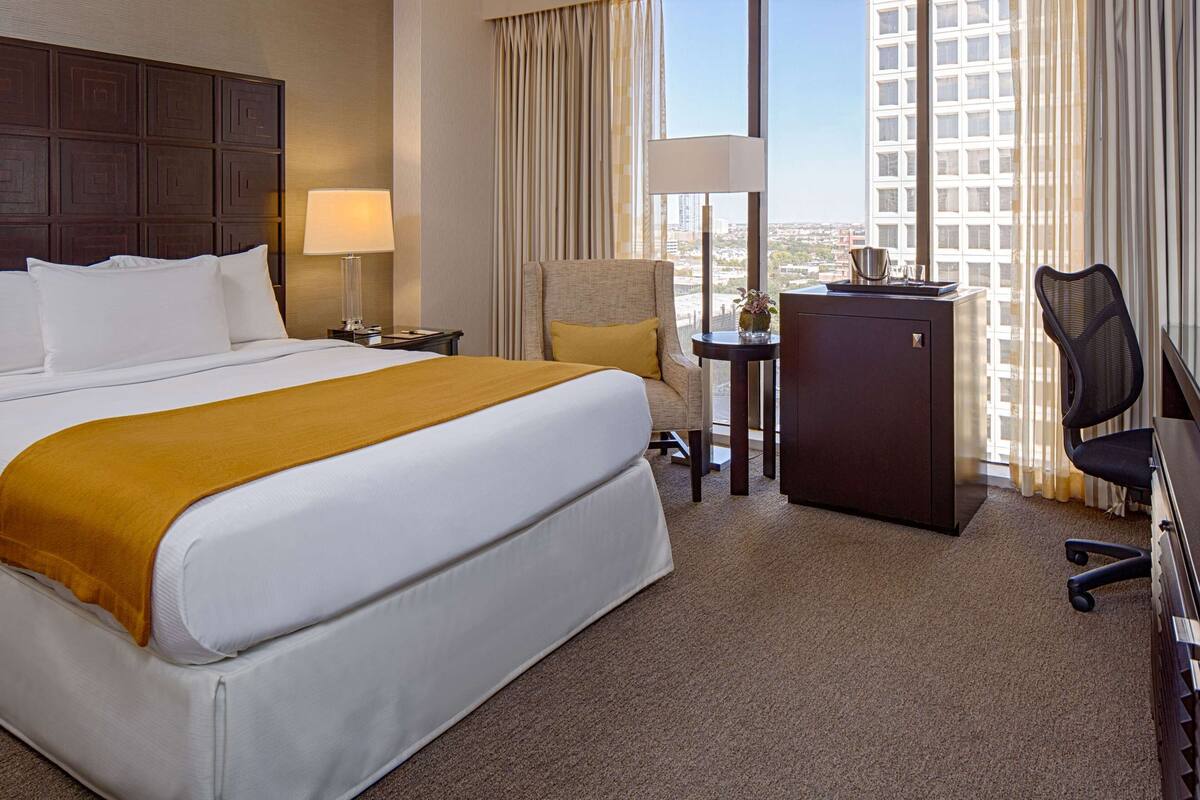 Une chambre d’hôtel avec un grand lit, un bureau équipé d’un ordinateur, une chaise et un téléviseur.