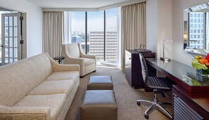 A hotel room with a sofa, armchair, desk, and a view of the cityscape. - DoubleTree by Hilton Hotel Houston - Greenway Plaza (Houston)