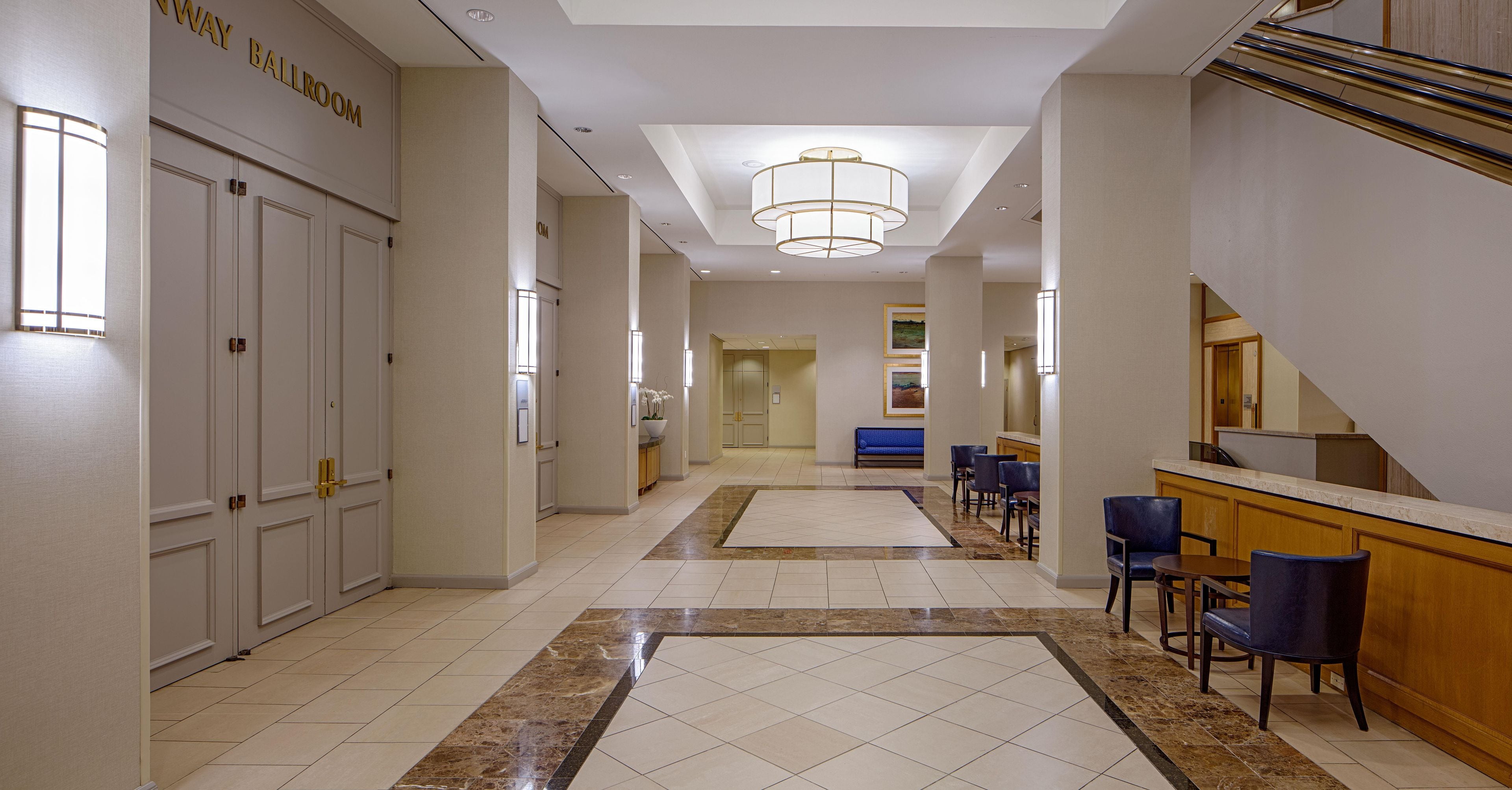Un vestíbulo de hotel con recepción, zona de estar y una escalera.