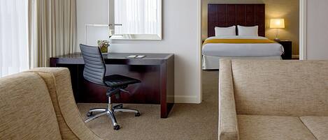 Ein Hotelzimmer mit Schreibtisch, zwei Sesseln, einem Bett und einem großen Spiegel.