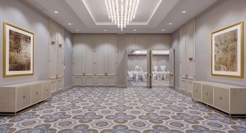A spacious room with a patterned floor, large doors, and a chandelier.