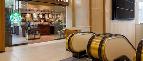 Una cafetería Starbucks con una escalera mecánica que lleva a la entrada.