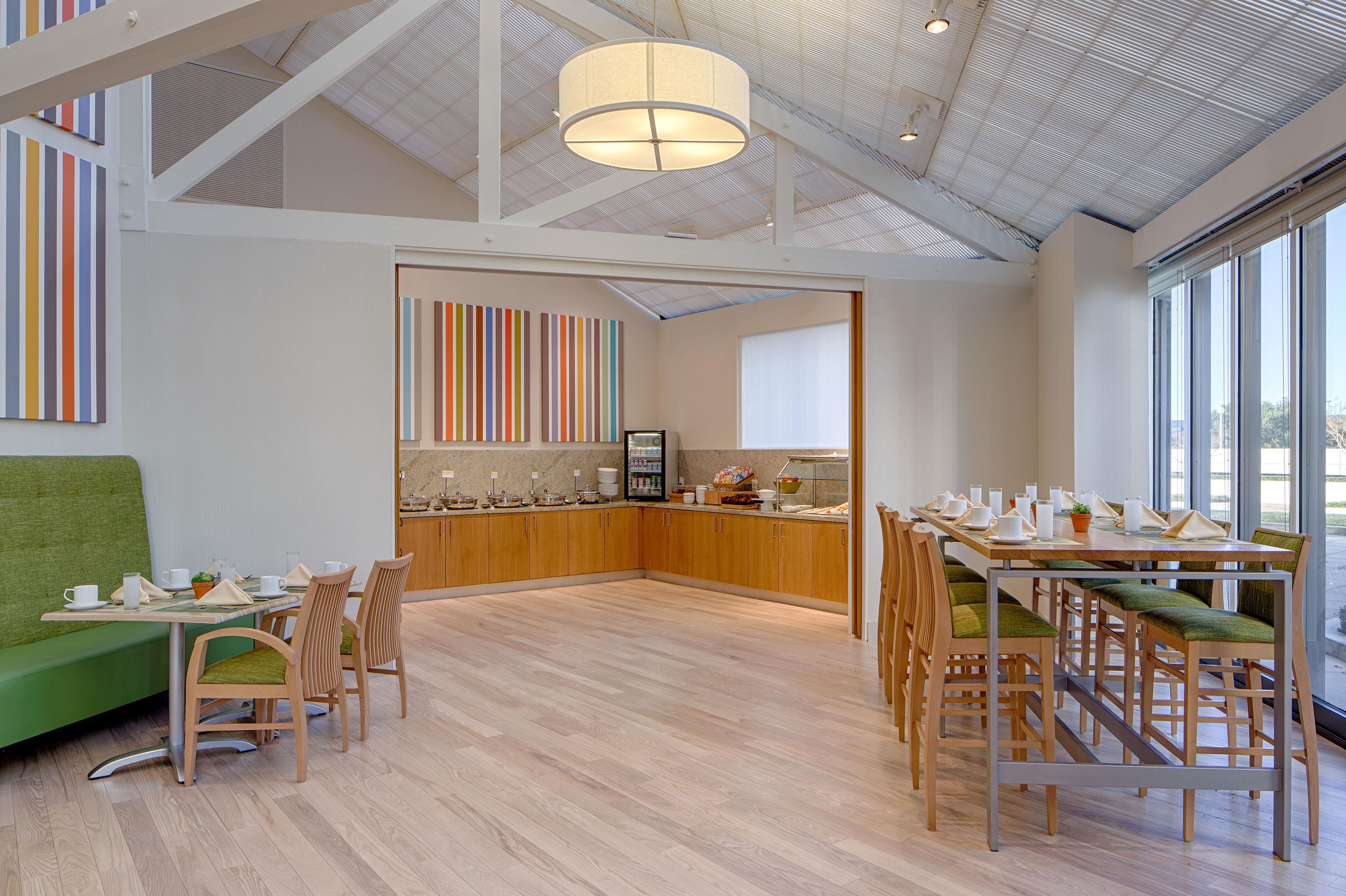 Un comedor moderno con mobiliario de madera, una isla central y vistas a través de amplios ventanales.