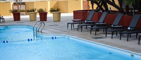 A swimming pool with lounge chairs and potted plants.