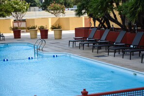 Una piscina con sillones de descanso y plantas en macetas.