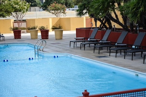 A swimming pool with lounge chairs and potted plants.