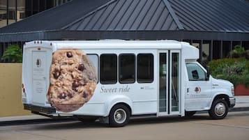 A white food truck with a large cookie advertisement on the side, parked in front of a building with a dark roof.