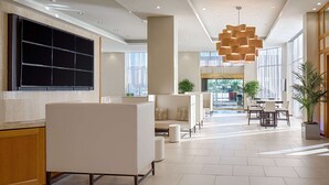 Un hall d’entrée spacieux avec un coin salon, un grand téléviseur à écran plat et un lustre moderne.