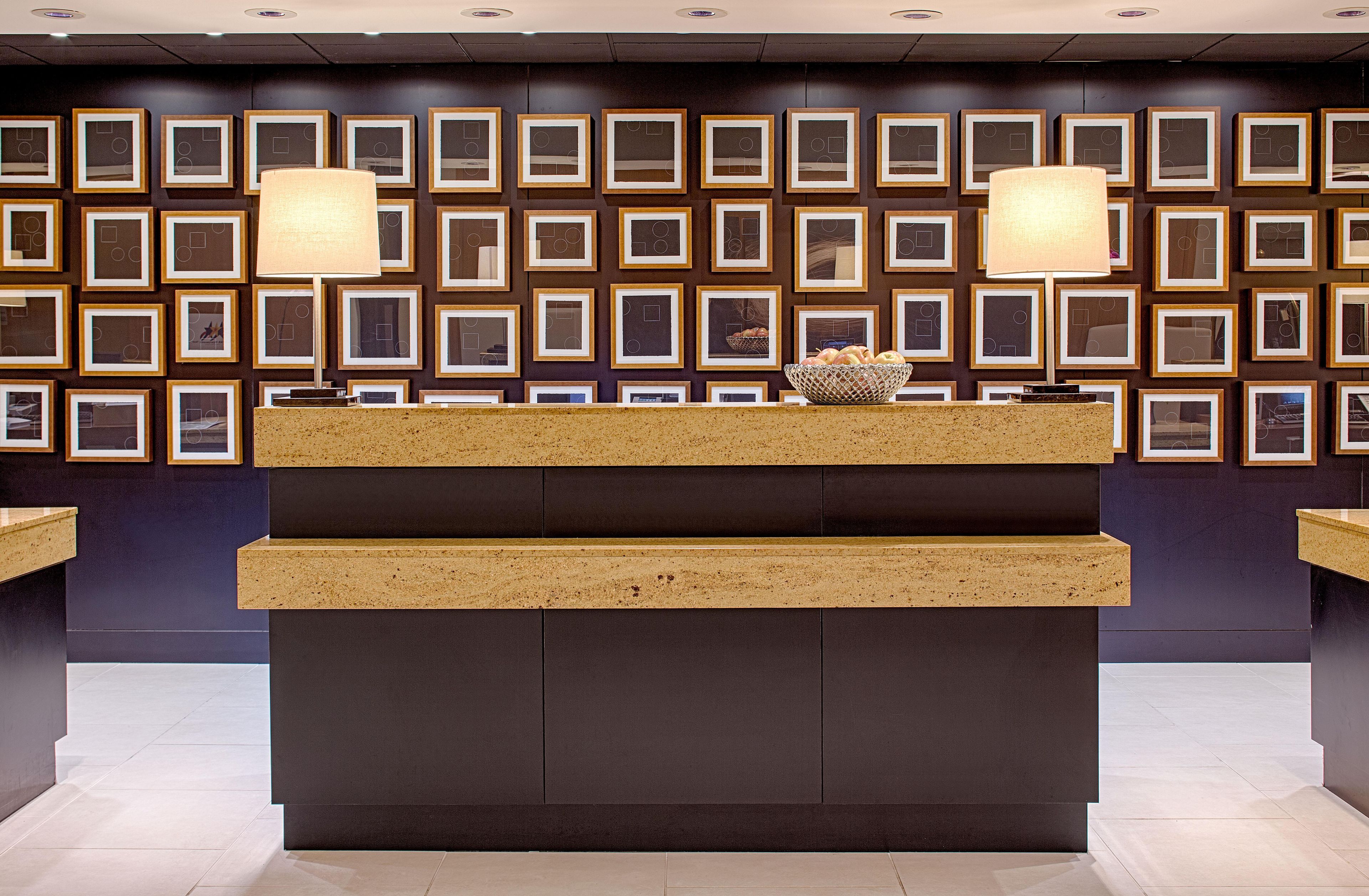 A reception desk with framed artwork on the wall behind it.