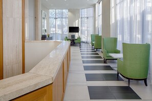 A reception area with a marble counter, green upholstered chairs, and a tiled floor. - DoubleTree by Hilton Hotel Houston - Greenway Plaza (Houston)