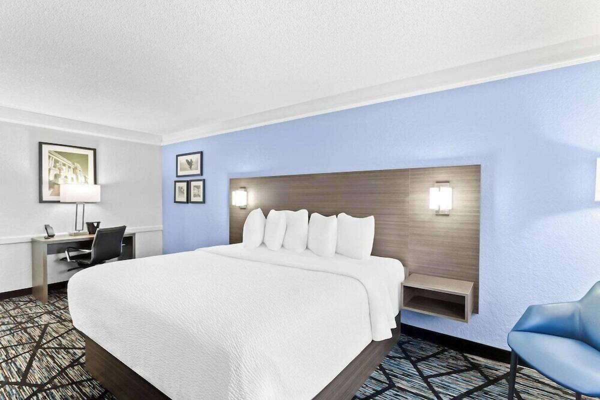 Une chambre d’hôtel équipée d’un lit, d’un bureau, d’une chaise et de lampes fixées au mur.