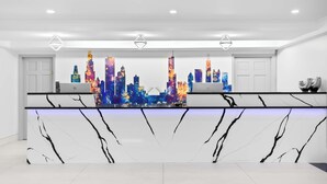 A modern reception desk with a cityscape mural, white marble design, and minimalistic decor.