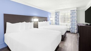 A hotel room with two beds, a TV, and a desk.