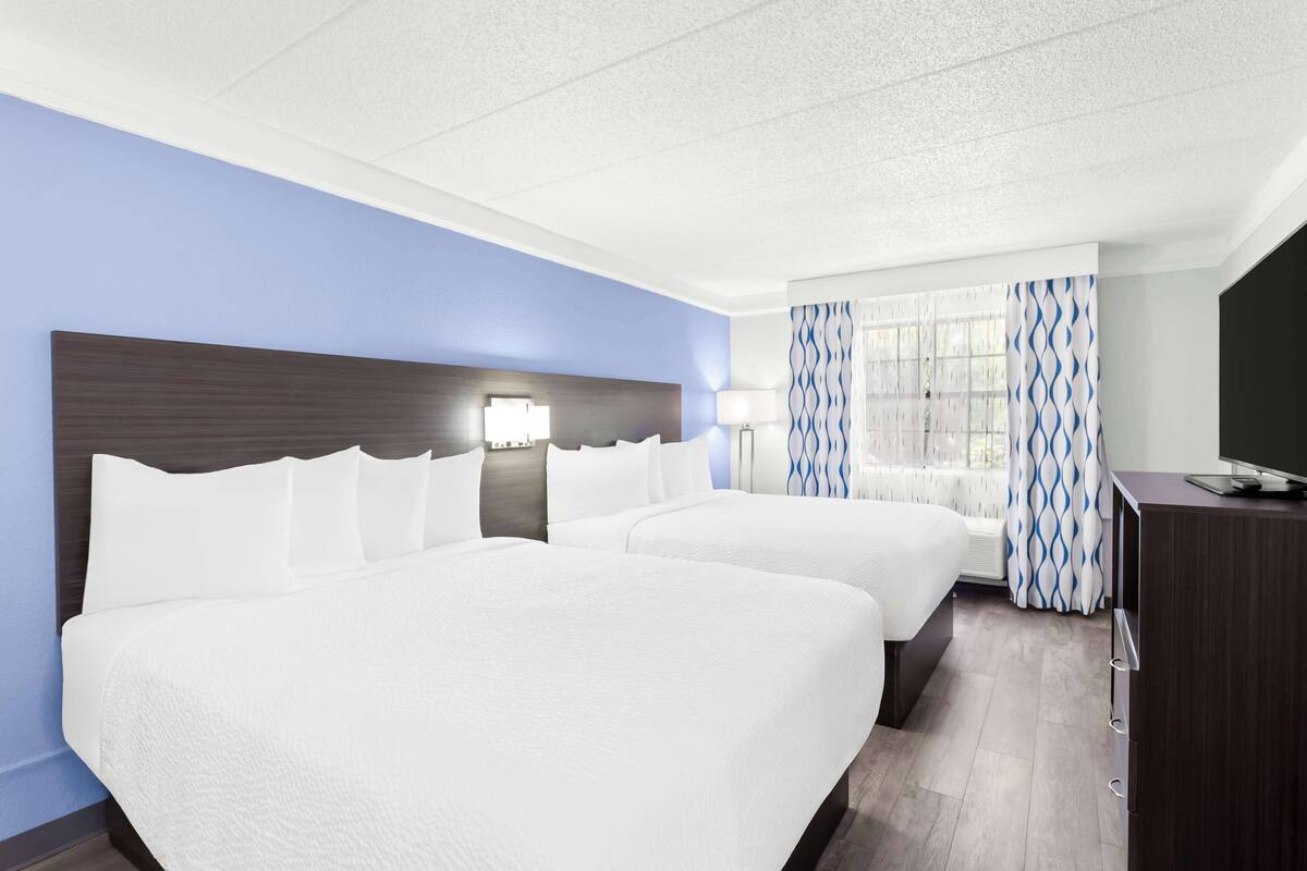 Une chambre d’hôtel avec deux lits, une télévision et un bureau.