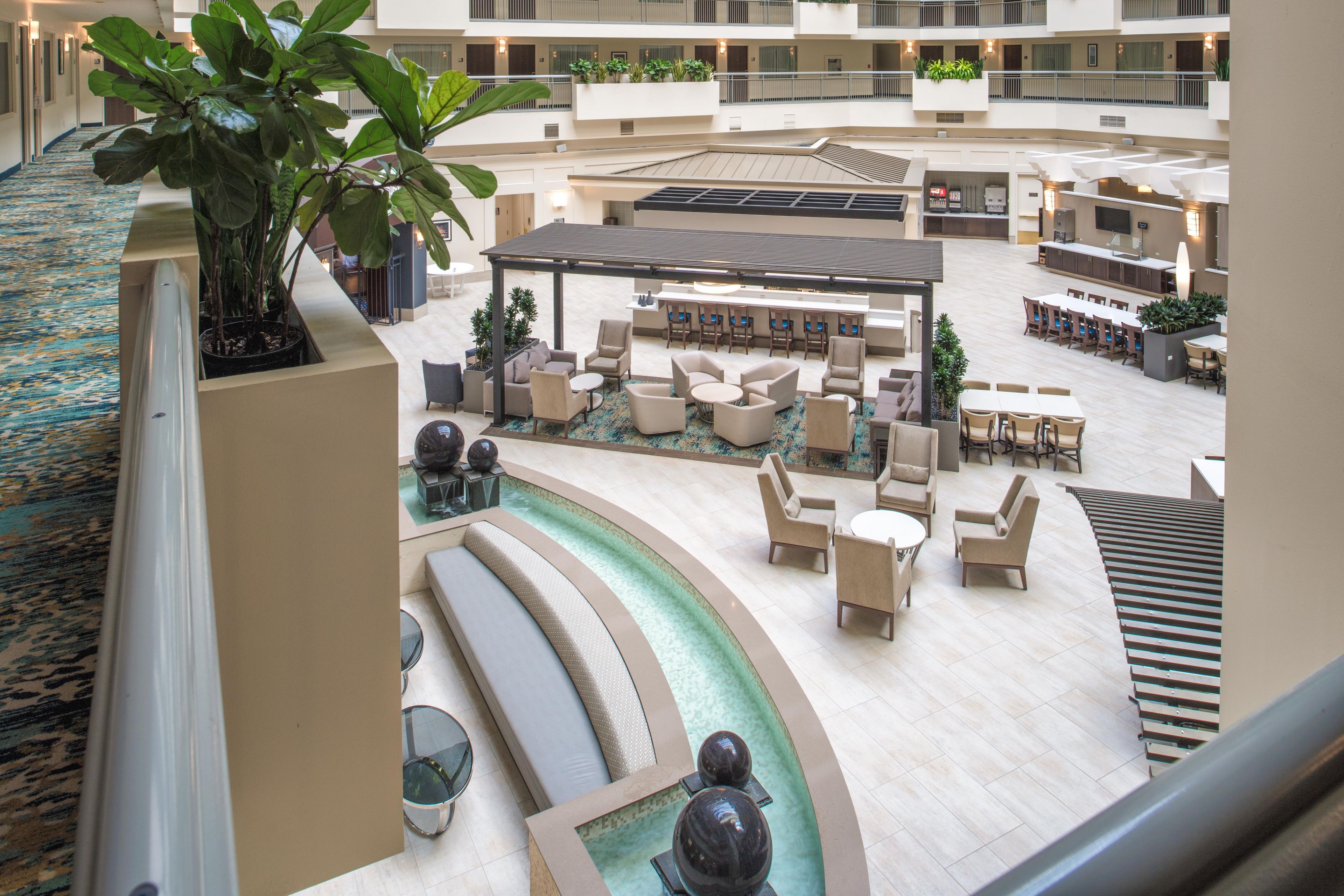 A hotel lobby with a pool area, seating arrangements, and a staircase.