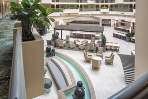 A hotel lobby with a pool area, seating arrangements, and a staircase. - Embassy Suites by Hilton Seattle Tacoma International Airport (Tukwila)