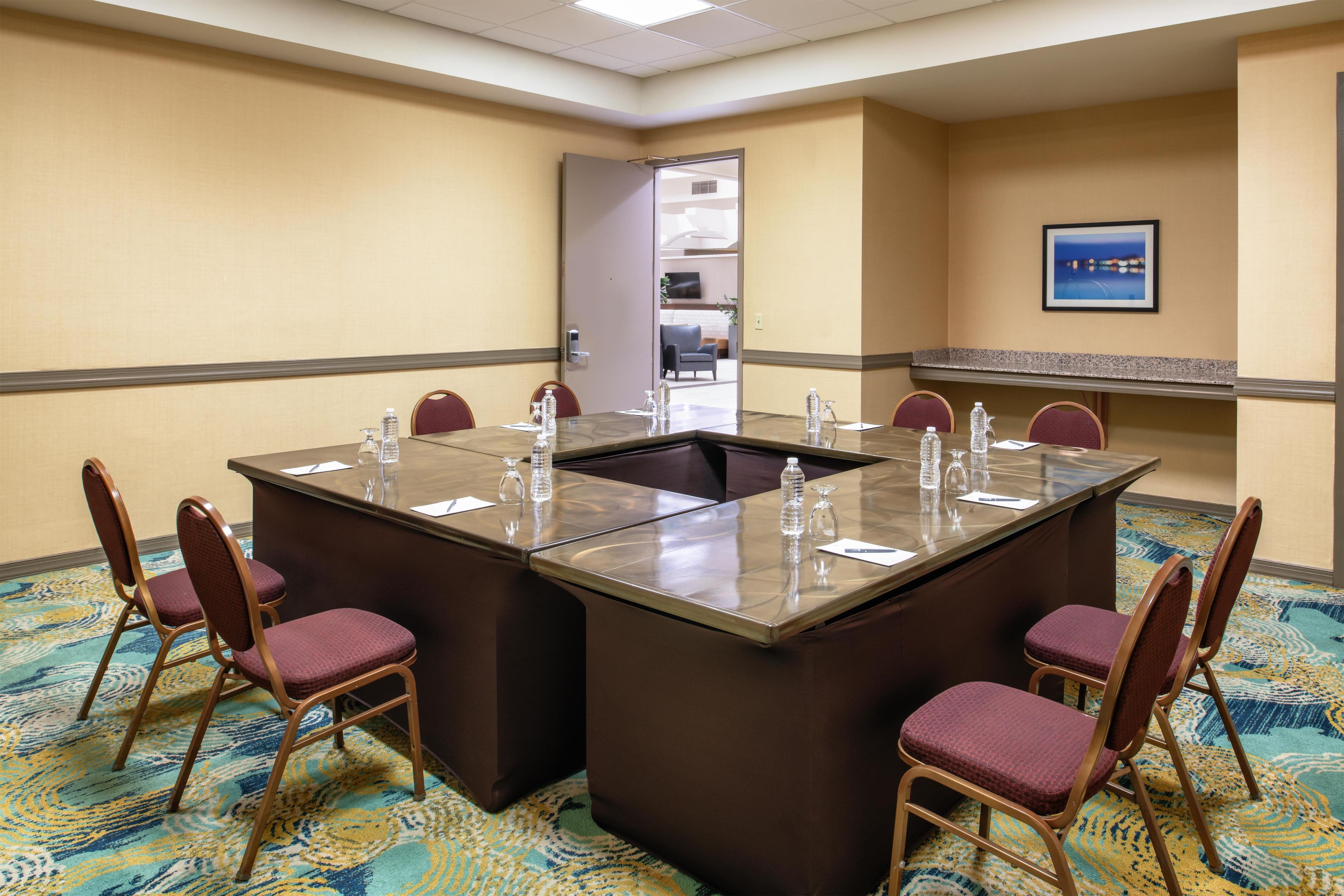 A conference room with a large rectangular table, six chairs, and water bottles on the table.