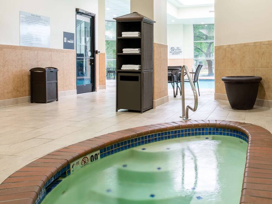 A pool area with a hot tub, a towel rack, and a trash bin.